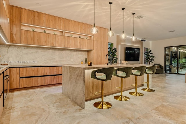 18269 SW 54th St, Miramar, FL 33029 - kitchen featuring decorative backsplash, modern cabinets, a kitchen breakfast bar, hanging light fixtures, and a kitchen island with sink
