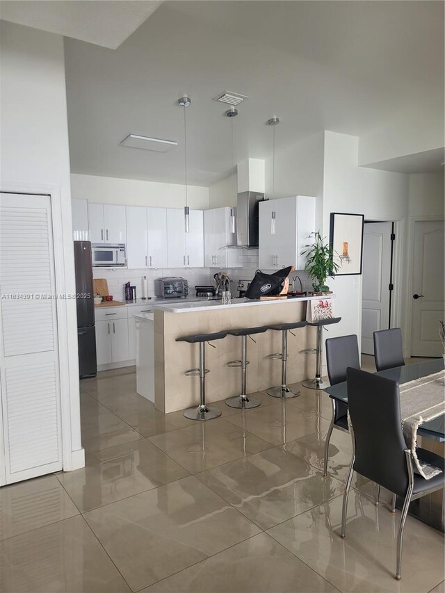 16909 SW 141st Ct, Miami, FL 33177 - kitchen with white microwave, freestanding refrigerator, a breakfast bar area, tasteful backsplash, and white cabinets