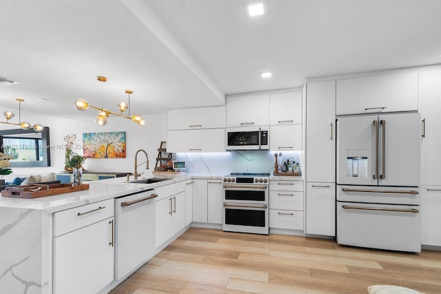 4000 NE 168th St Unit 113B, North Miami Beach, FL 33160 - kitchen featuring high end appliances, a peninsula, white cabinets, modern cabinets, and light wood-type flooring