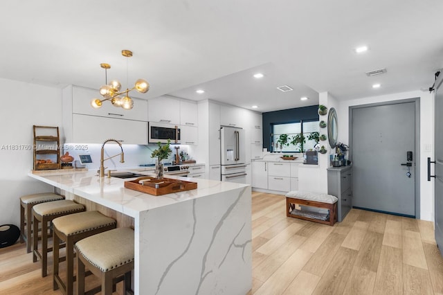 4000 NE 168th St Unit 113B, North Miami Beach, FL 33160 - kitchen with a peninsula, white microwave, light wood-style flooring, a breakfast bar, and modern cabinets