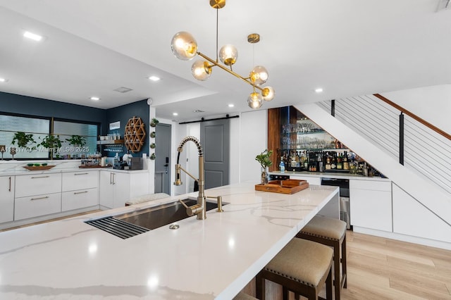 4000 NE 168th St Unit 113B, North Miami Beach, FL 33160 - kitchen with a barn door, white cabinets, modern cabinets, light stone countertops, and light wood finished floors