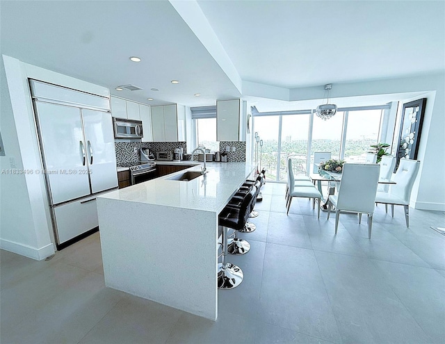 10275 Collins Ave Unit 722, Bal Harbour, FL 33154 - kitchen featuring stainless steel appliances, modern cabinets, tasteful backsplash, a kitchen bar, and light countertops