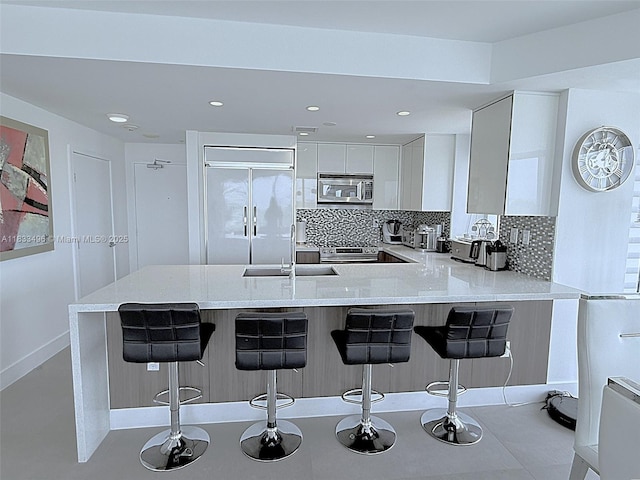 10275 Collins Ave Unit 722, Bal Harbour, FL 33154 - kitchen with stainless steel microwave, paneled refrigerator, a peninsula, tasteful backsplash, and recessed lighting