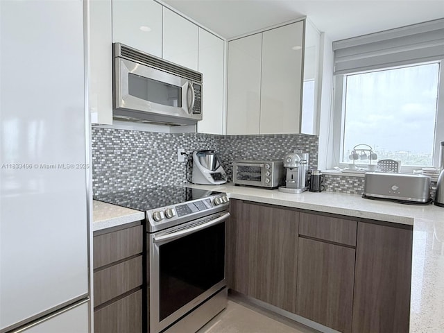 10275 Collins Ave Unit 722, Bal Harbour, FL 33154 - kitchen with appliances with stainless steel finishes, modern cabinets, backsplash, and white cabinets
