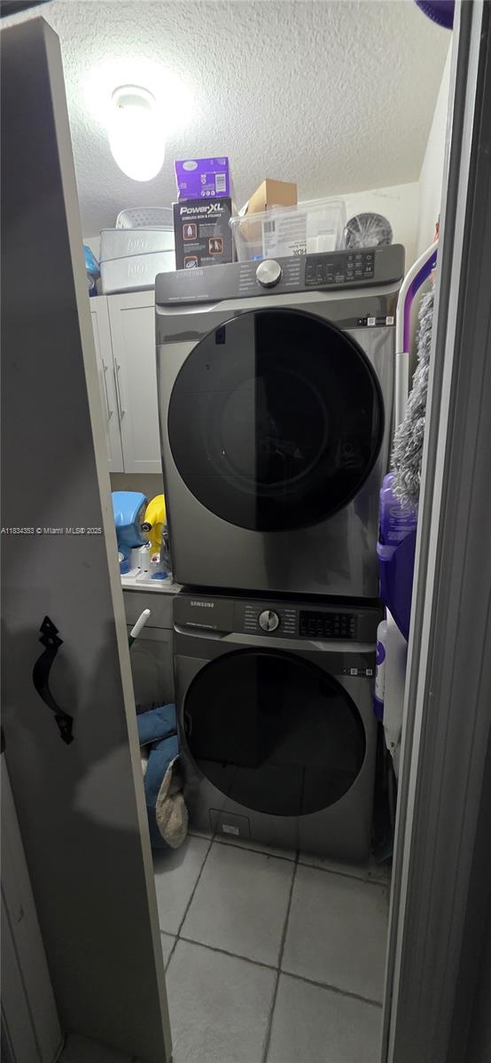 19185 SW 25th Ct, Miramar, FL 33029 - laundry room with stacked washing machine and dryer, cabinet space, tile patterned floors, and a textured ceiling