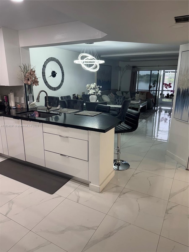 13355 SW 16th Ct Unit 105E, Pembroke Pines, FL 33027 - kitchen featuring white cabinets, dark countertops, light marble finish floors, modern cabinets, and a chandelier