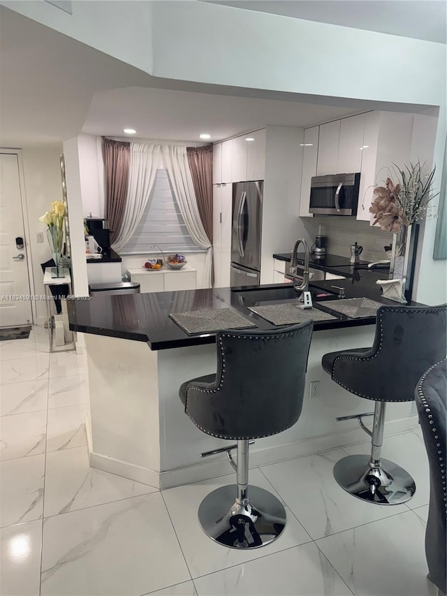13355 SW 16th Ct Unit 105E, Pembroke Pines, FL 33027 - kitchen with stainless steel appliances, light marble finish flooring, a kitchen bar, dark countertops, and modern cabinets