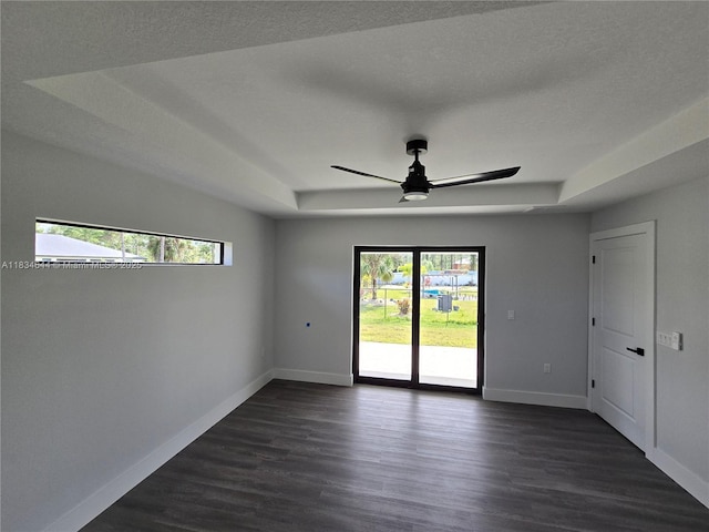 1605 W 11th St, Lehigh Acres, FL 33971 - empty room with a tray ceiling, a ceiling fan, and dark wood-style flooring