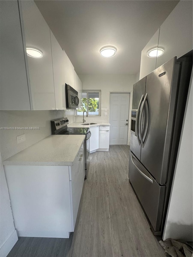 1812 NW 64th St, Miami, FL 33147 - kitchen with appliances with stainless steel finishes, wood finished floors, white cabinetry, and light countertops