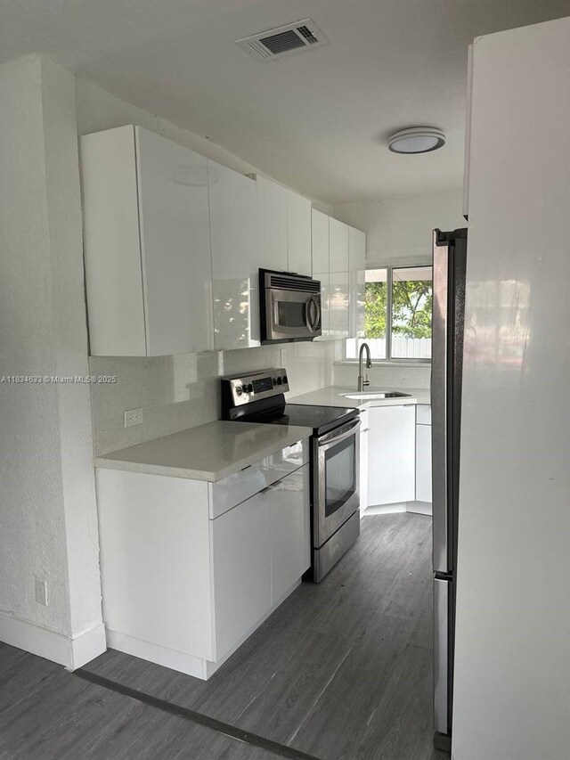 1812 NW 64th St, Miami, FL 33147 - kitchen featuring stainless steel appliances, dark wood-style flooring, modern cabinets, and white cabinets
