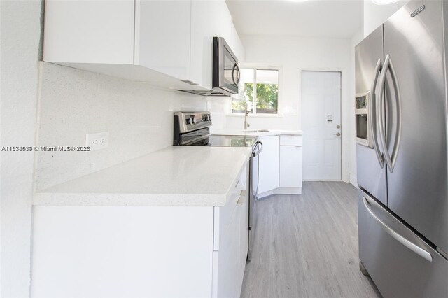 1812 NW 64th St, Miami, FL 33147 - kitchen with stainless steel appliances, white cabinetry, light wood-style flooring, and light countertops