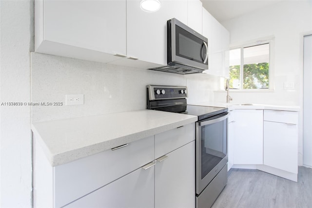 1812 NW 64th St, Miami, FL 33147 - kitchen featuring stainless steel appliances, white cabinetry, light wood-type flooring, modern cabinets, and light stone countertops