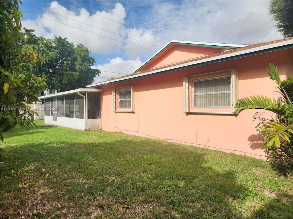 6900 NW 94th Ave, Tamarac, FL 33321 - view of home's exterior with a sunroom, stucco siding, and a yard