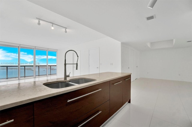 465 Brickell Ave Unit 4505, Miami, FL 33131 - kitchen with dark brown cabinetry, track lighting, modern cabinets, light stone counters, and light tile patterned floors