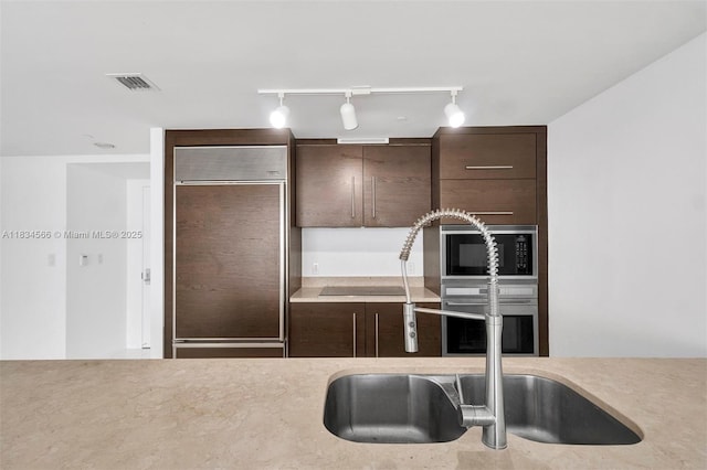 465 Brickell Ave Unit 4505, Miami, FL 33131 - kitchen featuring built in appliances, rail lighting, dark brown cabinets, and light countertops
