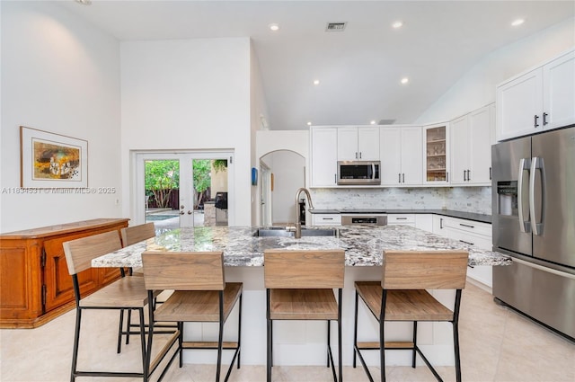 1583 SW 191st Ave, Pembroke Pines, FL 33029 - kitchen with appliances with stainless steel finishes, decorative backsplash, a breakfast bar area, white cabinetry, and light stone counters