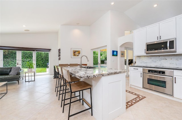 1583 SW 191st Ave, Pembroke Pines, FL 33029 - kitchen featuring appliances with stainless steel finishes, light tile patterned floors, tasteful backsplash, a breakfast bar, and high vaulted ceiling