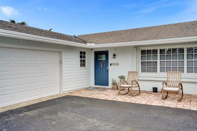 7735 Edgewater Dr, Lake Clarke Shores, FL 33406 - property entrance with a shingled roof, an attached garage, brick siding, and a porch