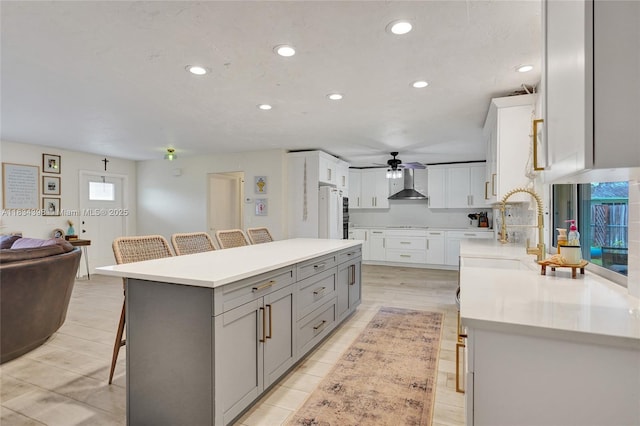 7735 Edgewater Dr, Lake Clarke Shores, FL 33406 - kitchen with a breakfast bar area, gray cabinetry, wall chimney exhaust hood, recessed lighting, and open floor plan