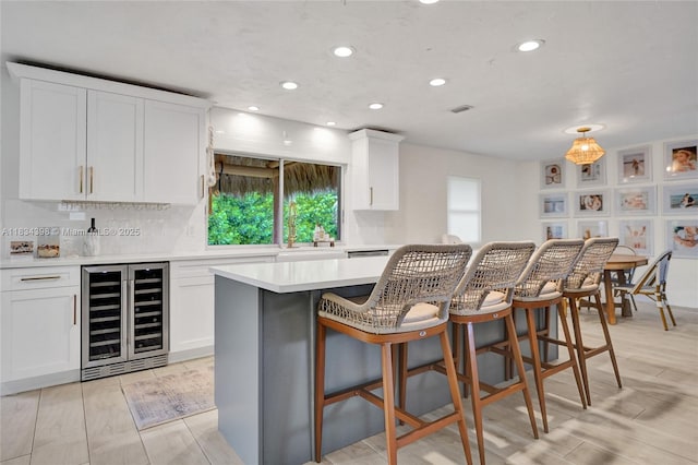 7735 Edgewater Dr, Lake Clarke Shores, FL 33406 - kitchen with wine cooler, recessed lighting, white cabinetry, light countertops, and a kitchen breakfast bar