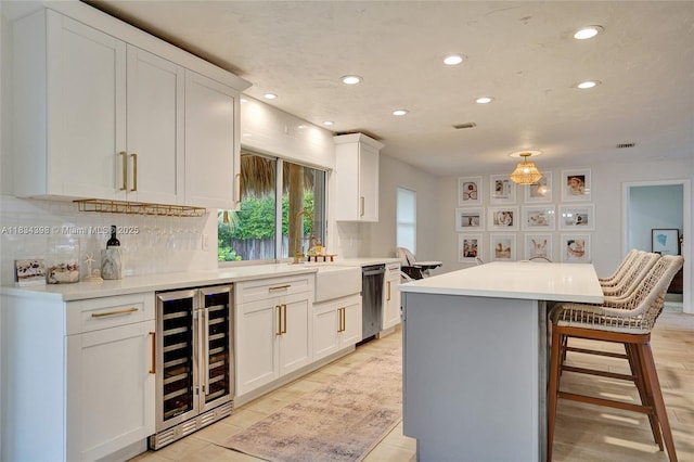 7735 Edgewater Dr, Lake Clarke Shores, FL 33406 - kitchen featuring wine cooler, dishwasher, recessed lighting, white cabinets, and a breakfast bar