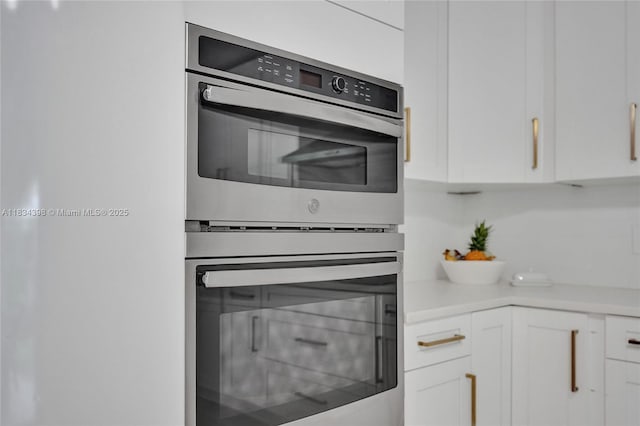7735 Edgewater Dr, Lake Clarke Shores, FL 33406 - kitchen with stainless steel double oven, white cabinets, and light countertops