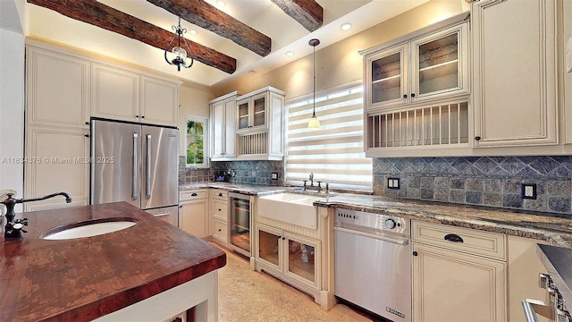 1111 Columbus Blvd, Coral Gables, FL 33134 - kitchen featuring stainless steel appliances, cream cabinetry, backsplash, beverage cooler, and beamed ceiling