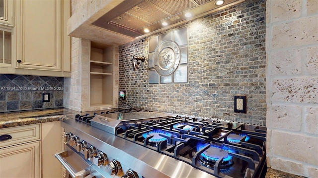 1111 Columbus Blvd, Coral Gables, FL 33134 - kitchen with cream cabinetry, stainless steel stove, wall chimney range hood, and tasteful backsplash