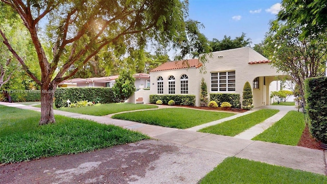 1111 Columbus Blvd, Coral Gables, FL 33134 - mediterranean / spanish-style home featuring a front lawn, a tiled roof, stucco siding, a carport, and driveway