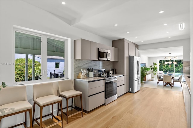 45 NE 104th St, Miami Shores, FL 33138 - kitchen with appliances with stainless steel finishes, gray cabinets, light wood-style floors, light countertops, and tasteful backsplash