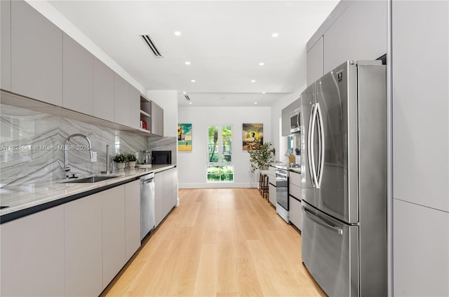 45 NE 104th St, Miami Shores, FL 33138 - kitchen with stainless steel appliances, modern cabinets, light wood-style floors, tasteful backsplash, and recessed lighting