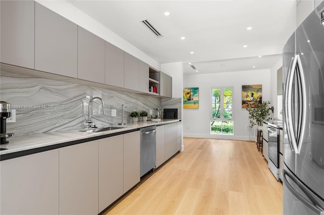 45 NE 104th St, Miami Shores, FL 33138 - kitchen featuring stainless steel appliances, modern cabinets, open shelves, decorative backsplash, and light wood-style floors