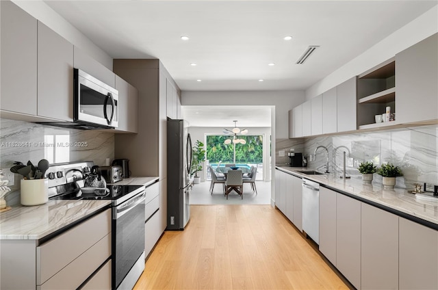 45 NE 104th St, Miami Shores, FL 33138 - kitchen featuring stainless steel appliances, open shelves, backsplash, recessed lighting, and light wood-type flooring