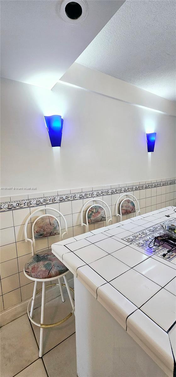 3494 E 4th Ave Unit 1207, Hialeah, FL 33013 - laundry room featuring tile walls, tile patterned floors, and a textured ceiling