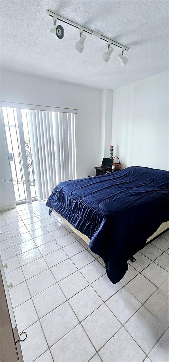 3494 E 4th Ave Unit 1207, Hialeah, FL 33013 - bedroom featuring track lighting, a textured ceiling, light tile patterned floors, and ceiling fan