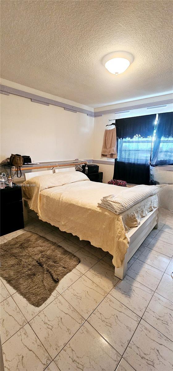 3494 E 4th Ave Unit 1207, Hialeah, FL 33013 - bedroom featuring a textured ceiling and marble look tiles
