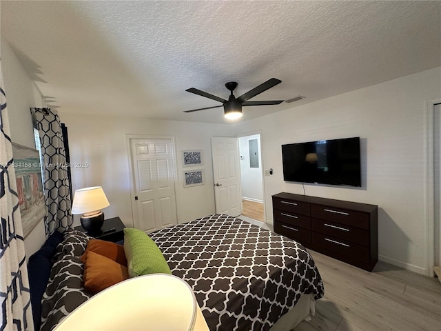 bedroom with light wood-type flooring, a textured ceiling, and ceiling fan
