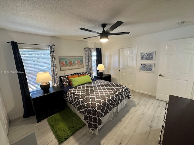 bedroom featuring light wood finished floors, ceiling fan, a textured ceiling, and a closet