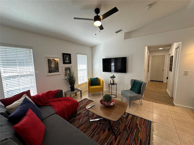 living area with vaulted ceiling, a textured ceiling, light tile patterned floors, and a ceiling fan