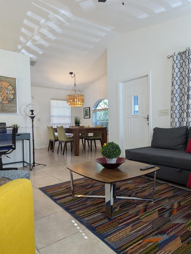 living area featuring light tile patterned floors, vaulted ceiling, and a chandelier