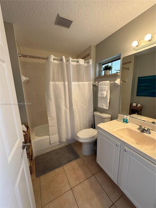 bathroom with a textured ceiling, vanity, shower / tub combo with curtain, and tile patterned flooring
