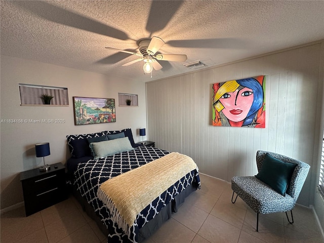 tiled bedroom with ceiling fan and a textured ceiling