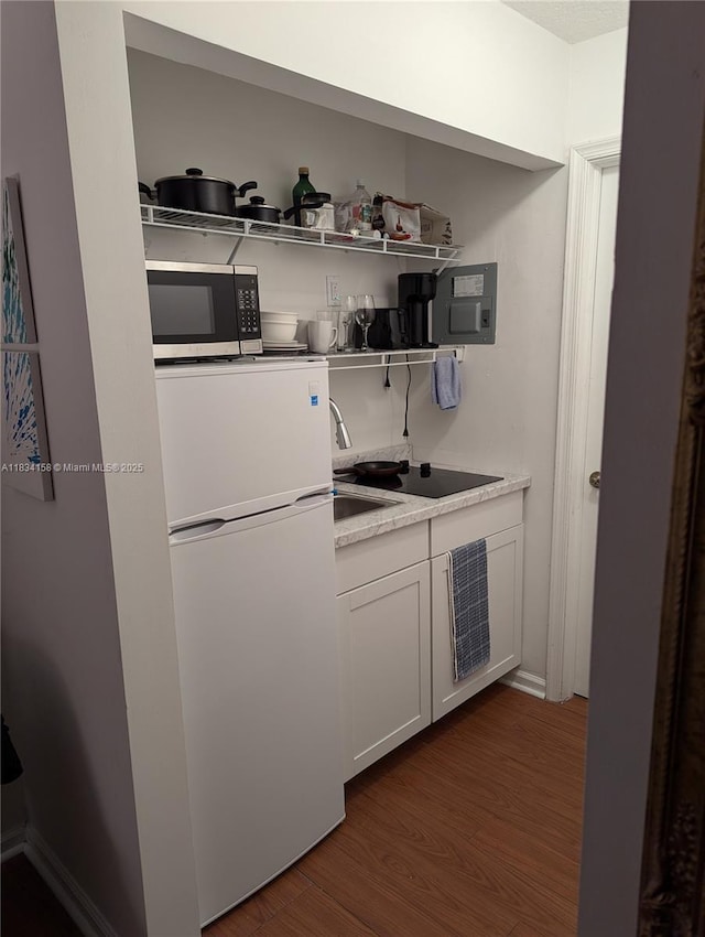 kitchen with stainless steel microwave, white fridge, dark wood-type flooring, light countertops, and open shelves