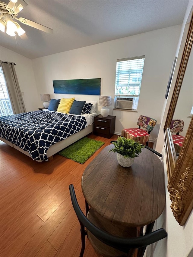 bedroom with cooling unit, wood finished floors, and ceiling fan