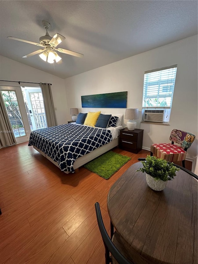bedroom featuring wood finished floors, multiple windows, access to exterior, vaulted ceiling, and ceiling fan