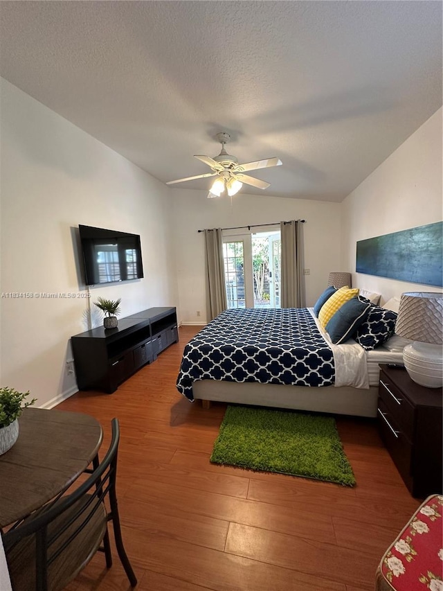 bedroom featuring wood finished floors, lofted ceiling, and ceiling fan