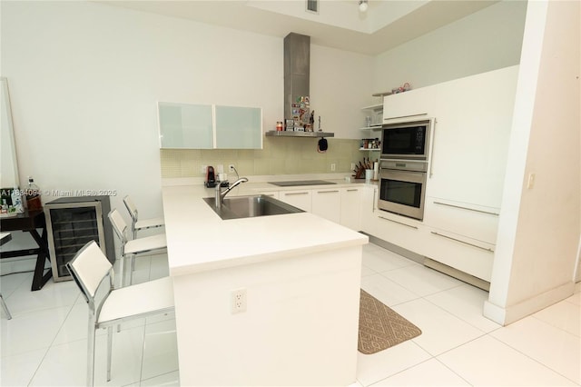 150 Sunny Isles Blvd Unit 1-Th403, Sunny Isles Beach, FL 33160 - kitchen featuring black appliances, exhaust hood, a peninsula, light countertops, and decorative backsplash