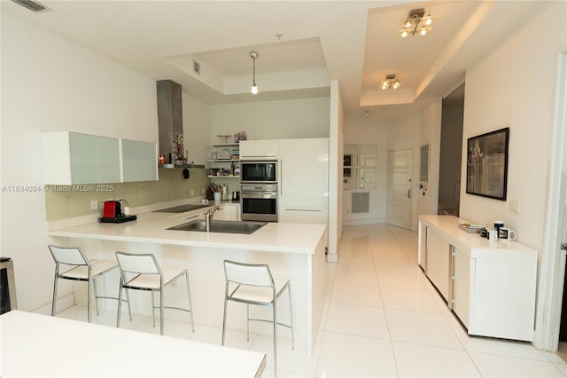 150 Sunny Isles Blvd Unit 1-Th403, Sunny Isles Beach, FL 33160 - kitchen featuring black appliances, a raised ceiling, a peninsula, a breakfast bar area, and decorative backsplash