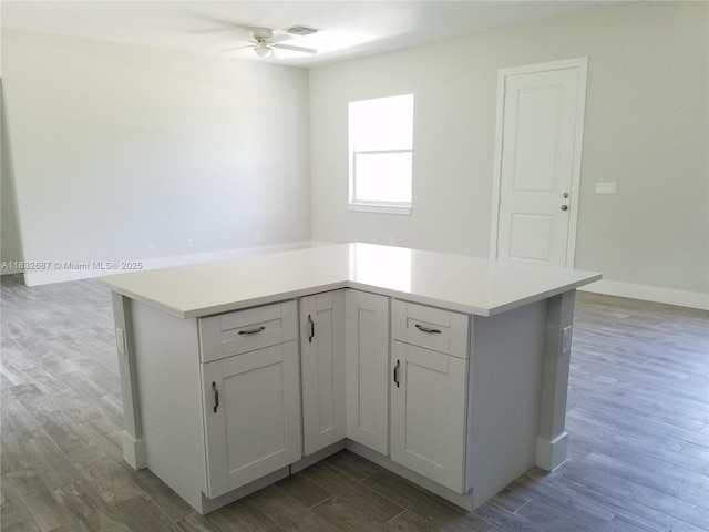 17186 N 84th Ct, Loxahatchee, FL 33470 - kitchen with a ceiling fan, wood finished floors, light countertops, white cabinets, and a kitchen island