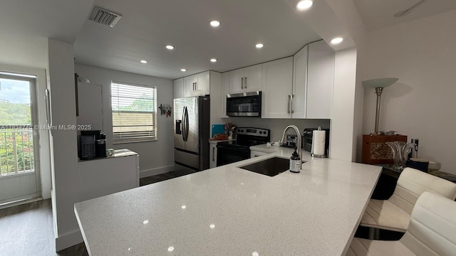 3910 Inverrary Blvd Unit 503-B, Lauderhill, FL 33319 - kitchen featuring appliances with stainless steel finishes, recessed lighting, white cabinets, a peninsula, and light stone counters